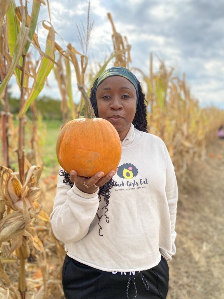 woman holding a pumpkin in a pumpkin patch