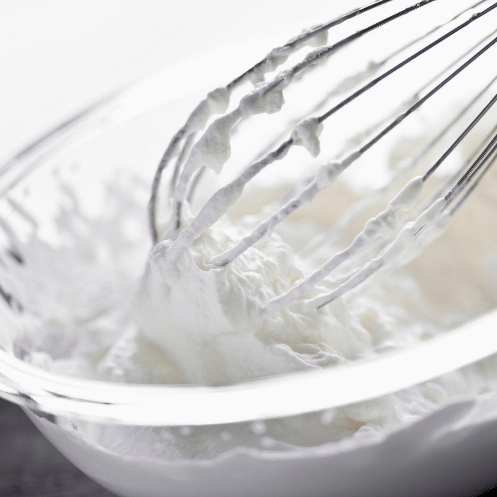 Picture of a whisk in a bowl of whipped cream for the parfait.