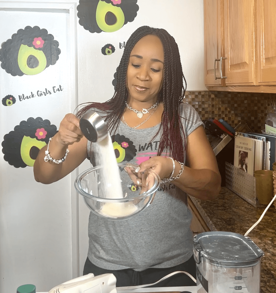 woman pouring sugar into a glass bowl
