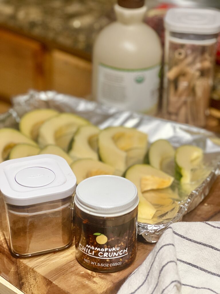 Spicy Maple Acorn Squash ingredients on a table including Chili Oil, Maple Syrup and Cinnamon